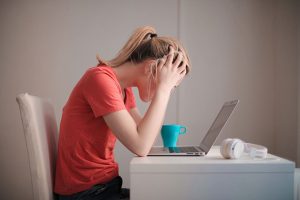 A woman appears stressed as she looks at her laptop