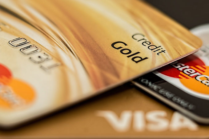 A close-up photo of a stack of gold and black coloured Visa and Mastercards