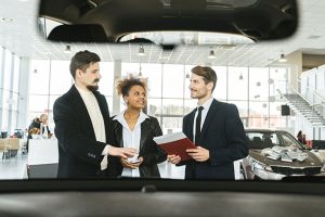 Couple at a car dealership discussing financial data with a salesperson